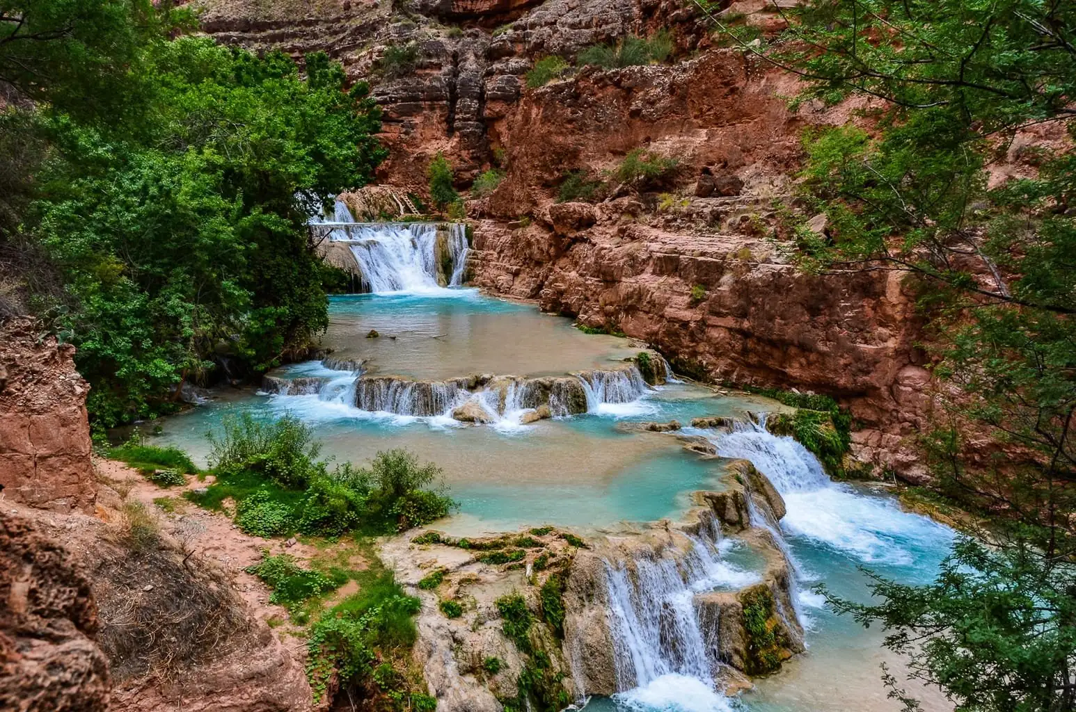 The terraced turquoise cascades of Beaver Falls between red canyon walls