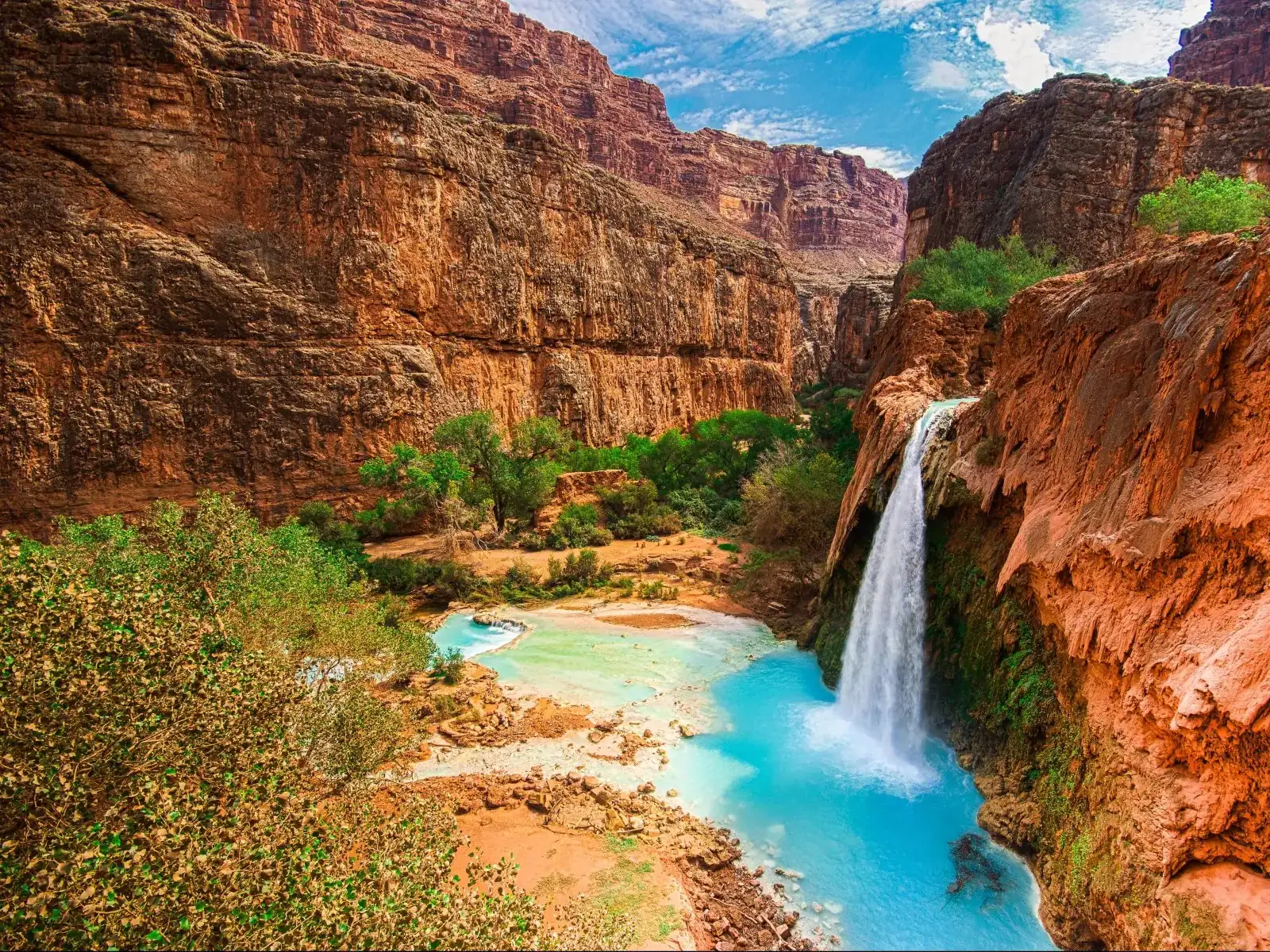 Havasu Falls pouring over red travertine into a turquoise pool in Havasu Canyon