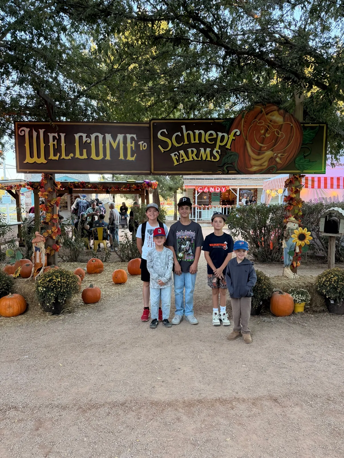 The crew under the Welcome to Schnepf Farms sign, ringed with pumpkins and fall garlands
