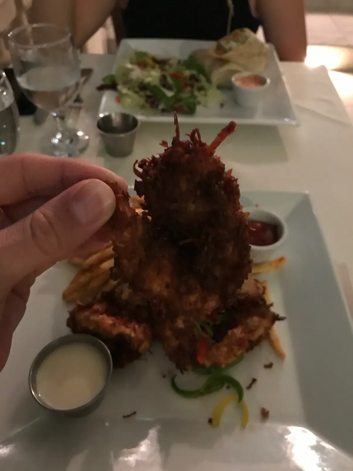 A plate of cracked conch with dipping sauce, held over a dinner table
